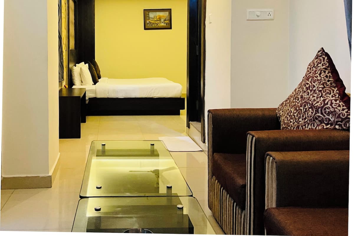 Una habitación de hotel con cama, sofá, mesa de centro de cristal y ventilador de techo.