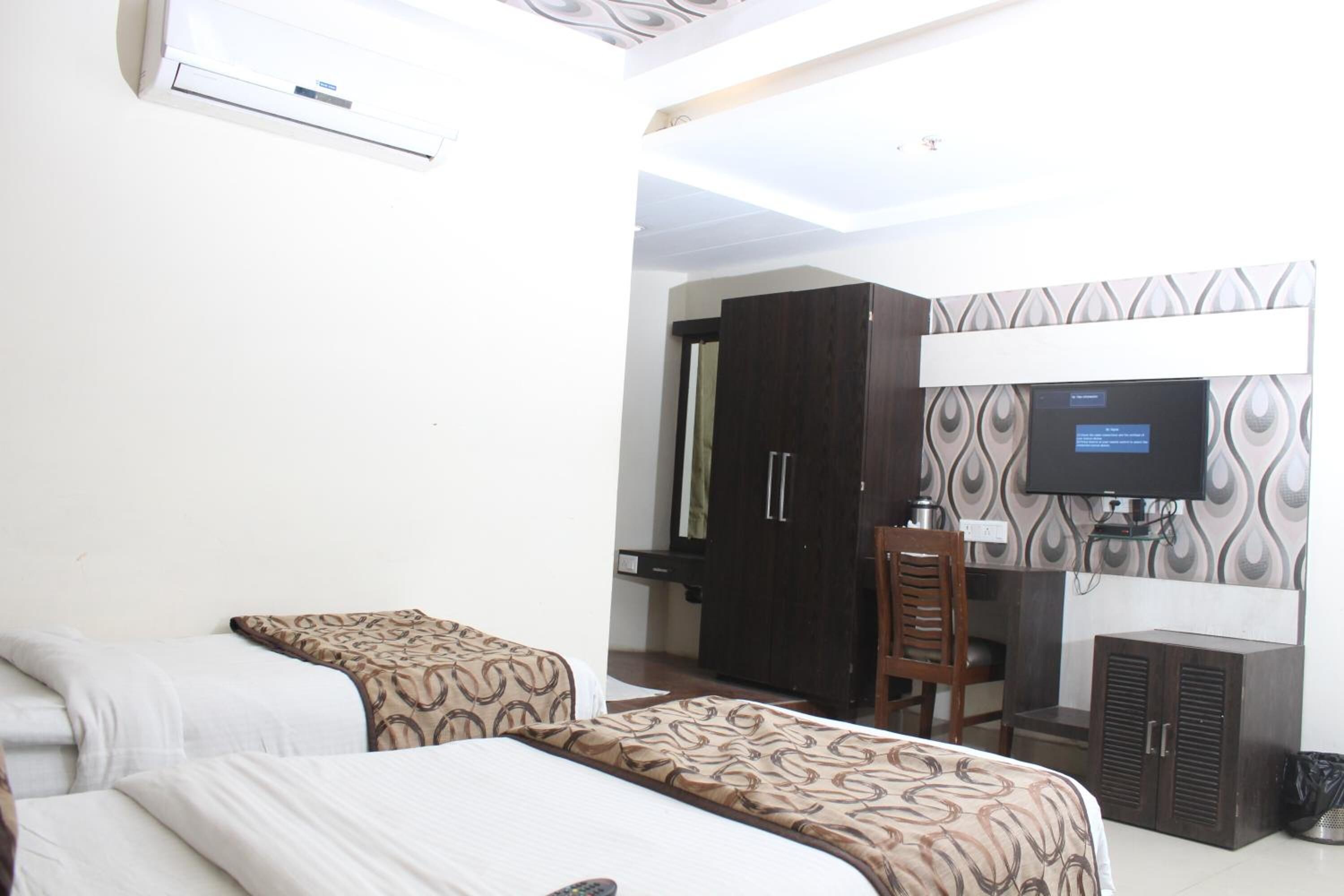 A hotel room with two beds, a TV, a desk, and a wardrobe.