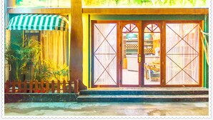 A building with a large glass door, a wooden fence, and a green and white striped awning. - Edinburgh Hostel (Zhangjiajie)