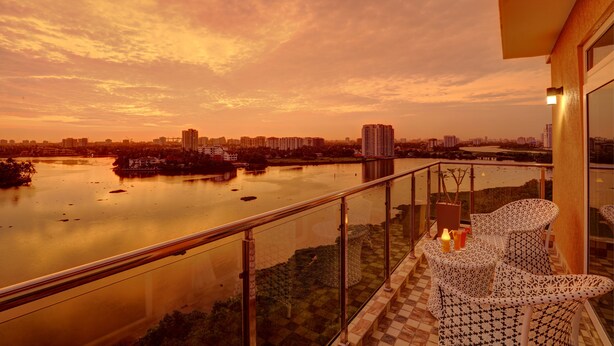 A balcony with a view of a river and cityscape at sunset. - JVK Park Hotel (Kanayannur)