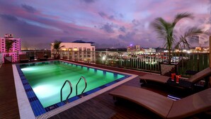 A rooftop pool with lounge chairs and a view of the cityscape at dusk. - JVK Park Hotel (Kanayannur)