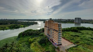 A high-rise hotel with a terrace overlooking a river, surrounded by greenery. - JVK Park Hotel (Kanayannur)