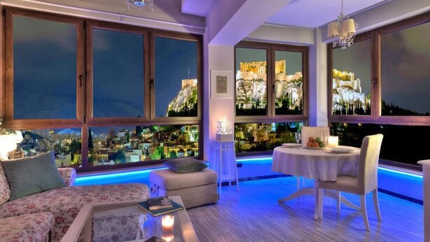 Una stanza con divano, tavolo da pranzo e vista sulla città illuminata di notte.