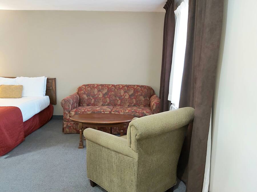 Una habitación de hotel con una cama, un sofá, una mesita y una silla.