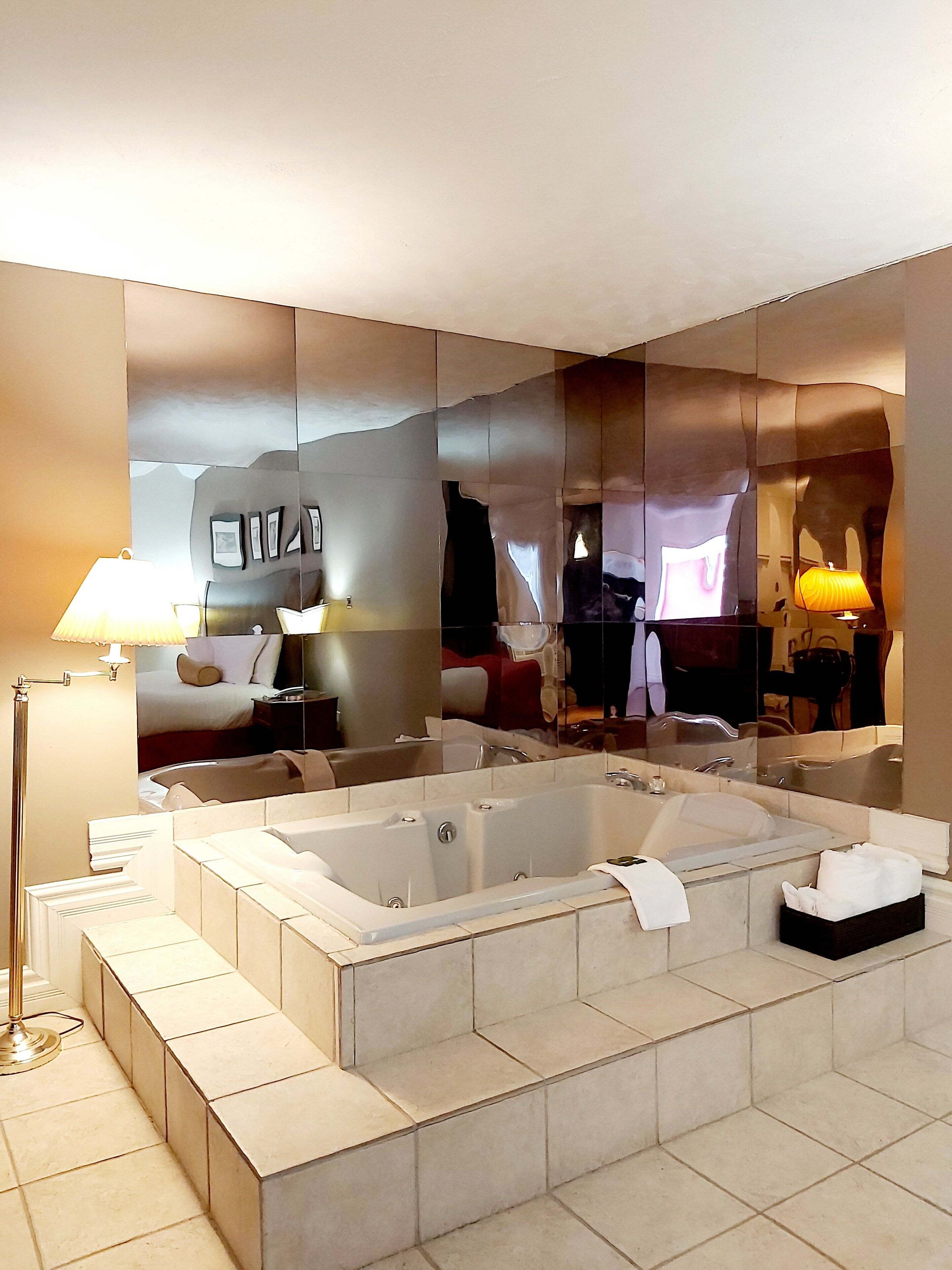Un baño moderno con una bañera grande, un espejo y una lámpara de pie.