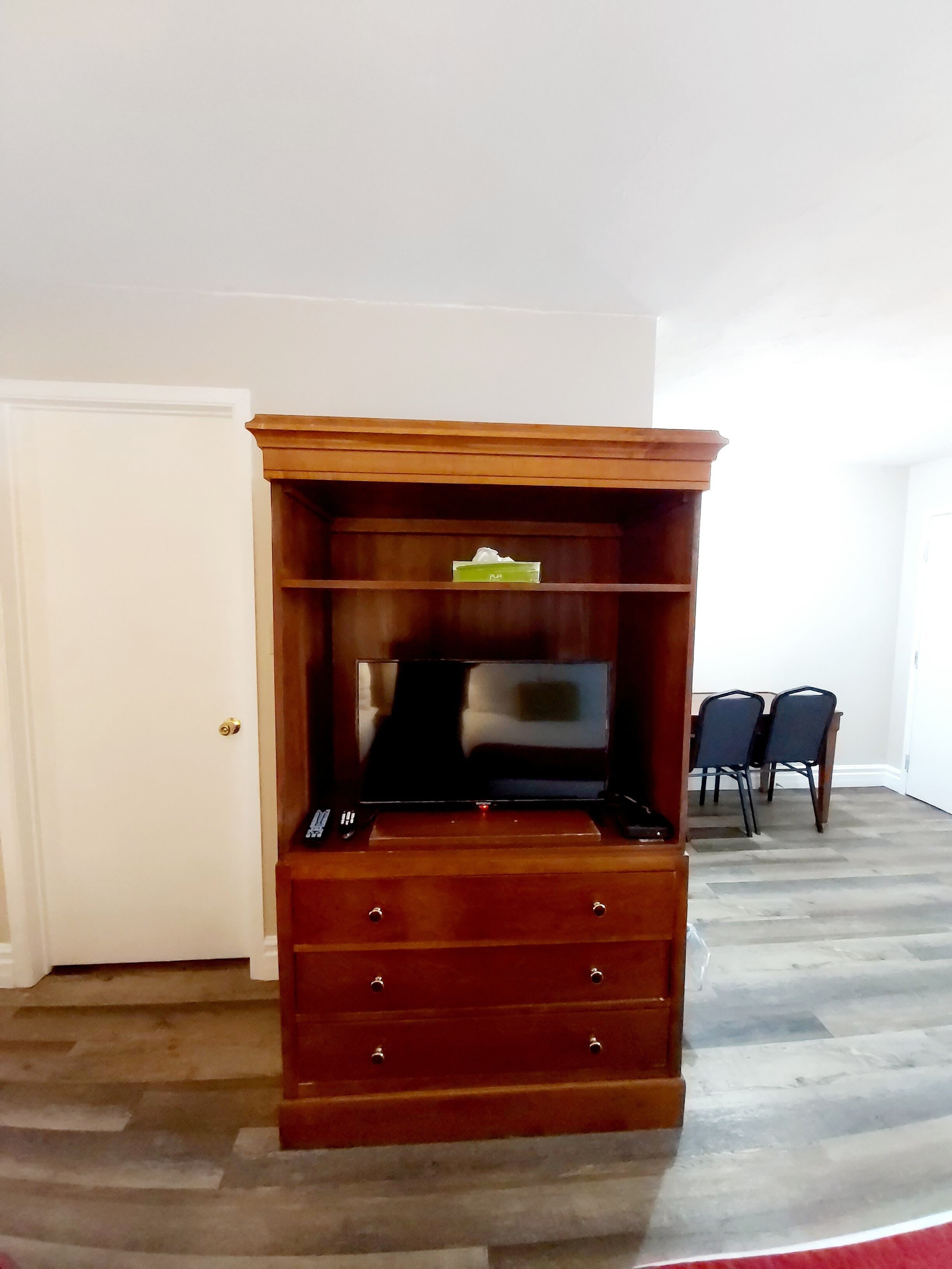 A wooden entertainment center with a TV, drawers, and a shelf.