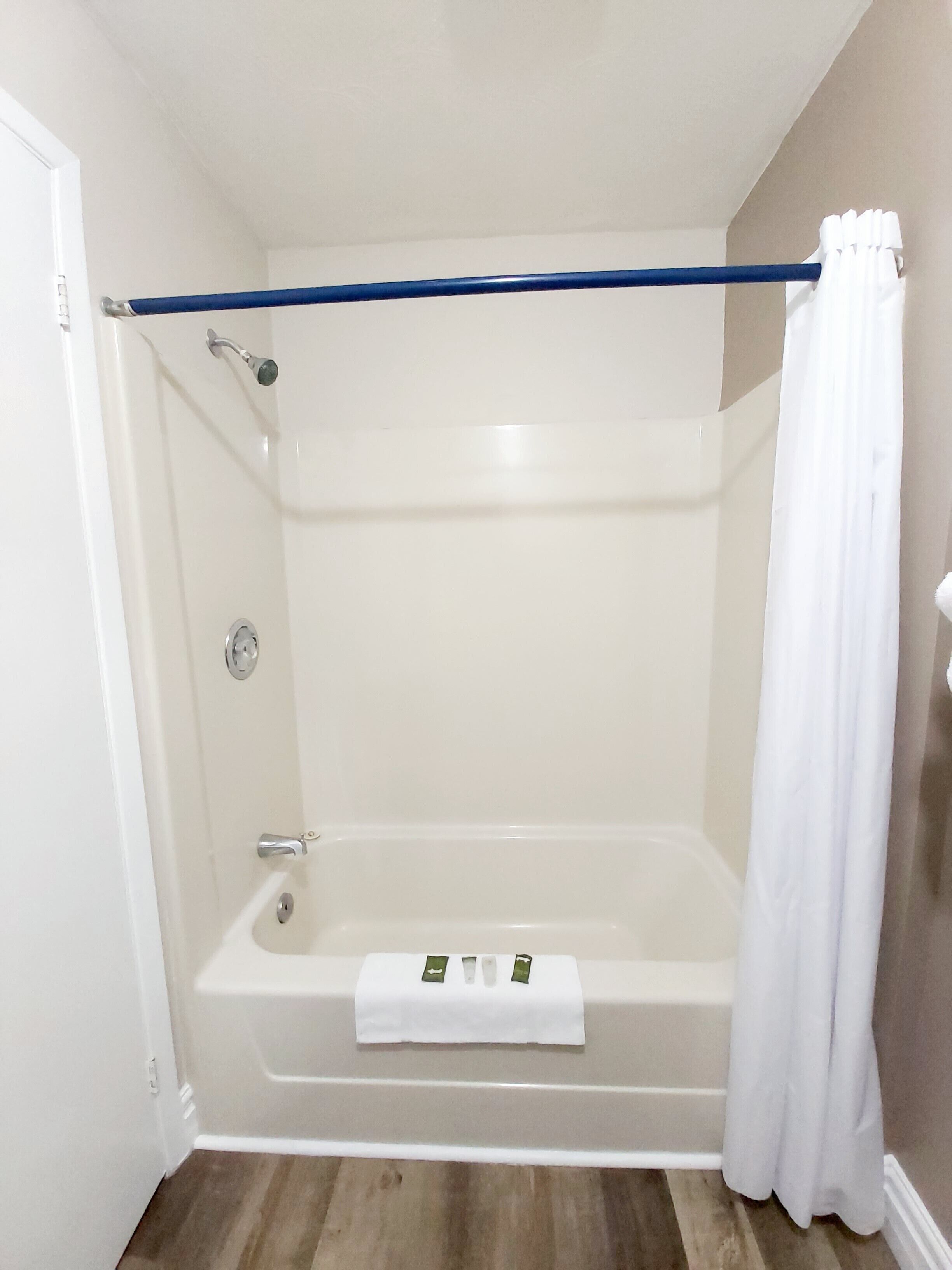 A bathroom with a bathtub, a shower, and a curtain.