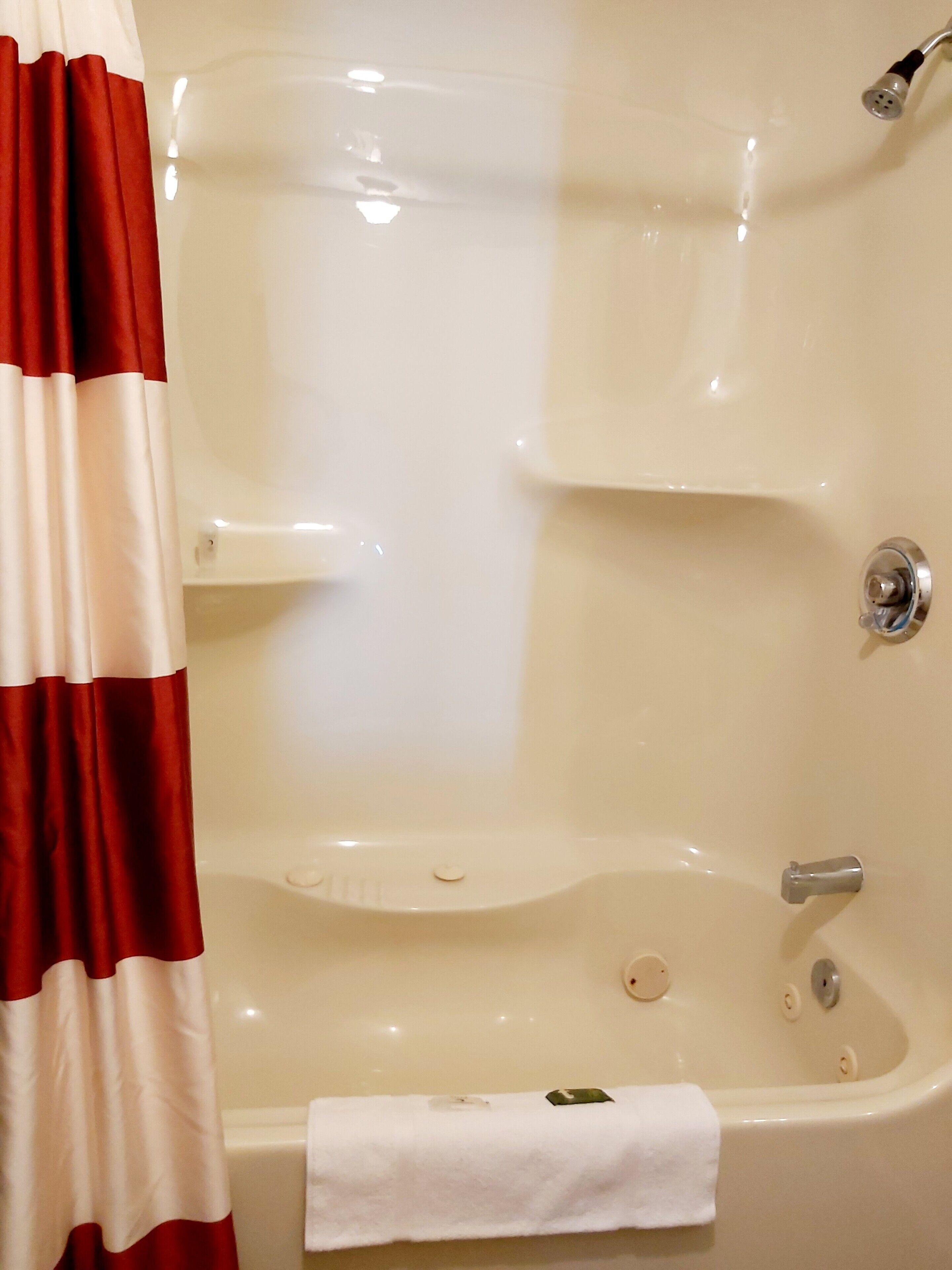 Une baignoire avec une serviette blanche, une pomme de douche et un robinet.