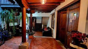 A hotel corridor with a wooden ceiling, a bicycle, potted plants, and a staircase.