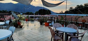 A terrace with tables and chairs, potted plants, and a mountainous backdrop. - Hotel Real Antigua (Antigua Guatemala)