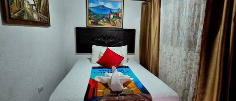 Habitación de hotel con cama, cabecera, almohada, manta, pintura en la pared y cortinas.