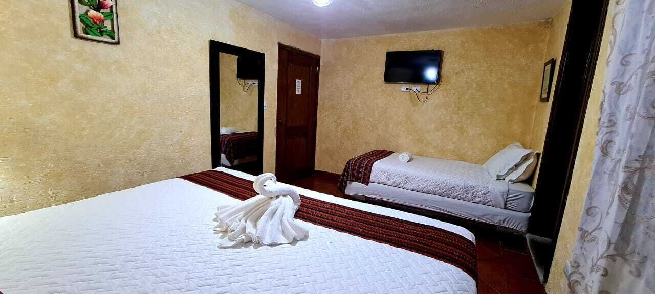 Habitación de hotel con dos camas, un televisor de pantalla plana y un espejo.