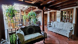 A room with a wooden ceiling, a patterned sofa, and hanging plants.