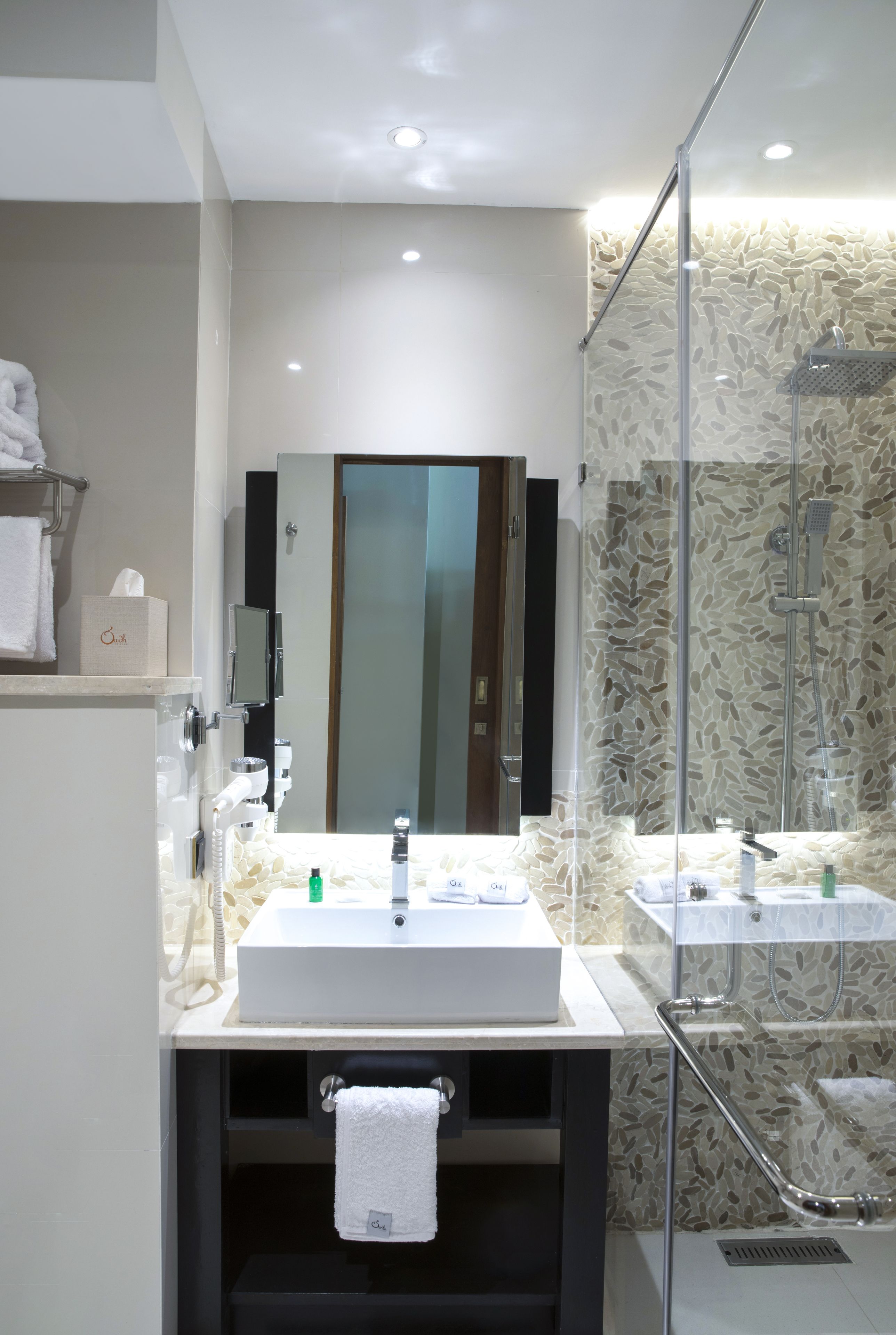 Un baño moderno con lavamanos doble, cabina de ducha con mampara de vidrio, espejo grande y barra para toallas.