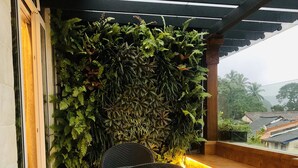 Un baño moderno con una bañera grande, un sillón de mimbre y una pared cubierta de plantas verdes.