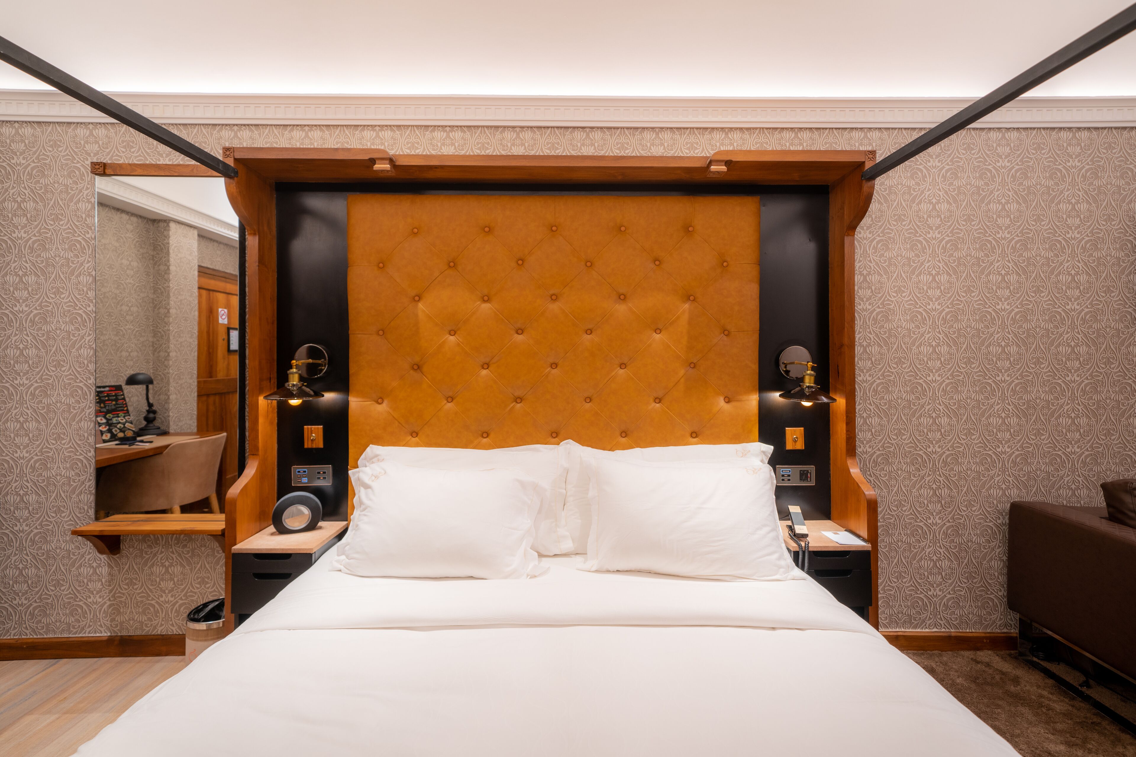 A hotel room with a large bed, a wooden headboard, two bedside tables, and a nightstand.
