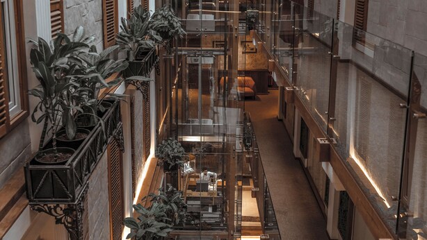 Un amplio atrio con techos altos, una escalera central y varios balcones con plantas en macetas.