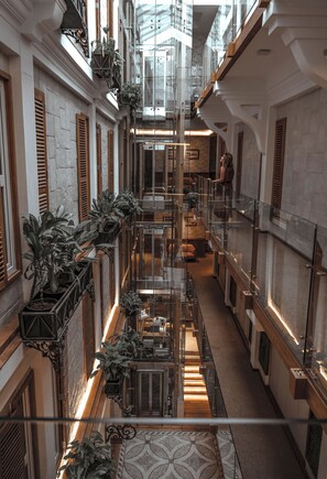 Un amplio atrio con techos altos, una escalera central y varios balcones con plantas en macetas.