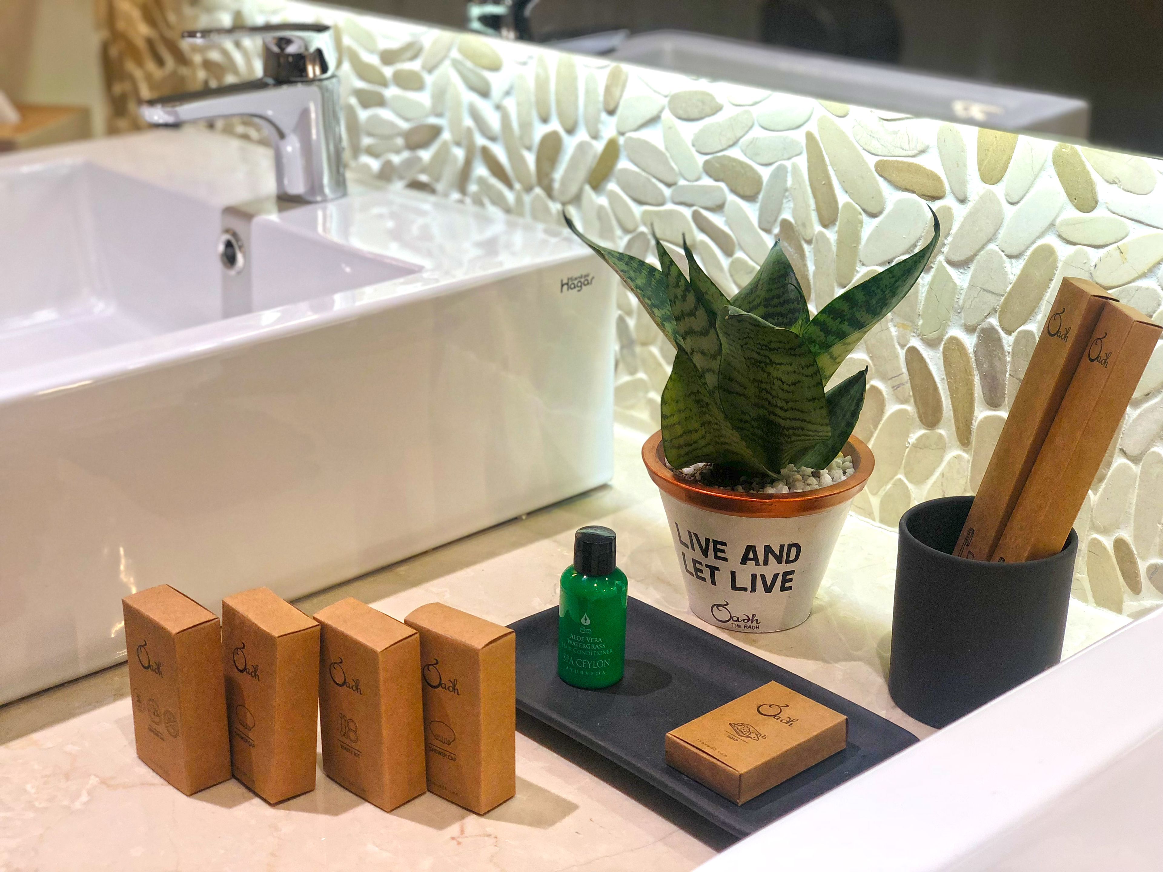 Une salle de bain avec une baignoire blanche, une plante en pot et plusieurs bâtonnets de bois dans un support.