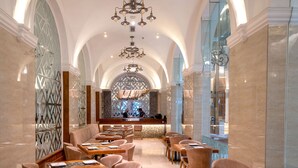 Un restaurante espacioso con techos altos, ventanas arqueadas y una zona de bar central.