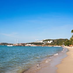 Na praia, areia branca, espreguiçadeiras, guarda-sóis