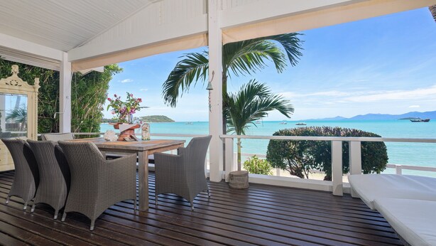 A covered outdoor area with a wooden deck, wicker furniture, and a view of the ocean. - Ban Mok Talay Beachfront Villa (Koh Samui)