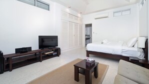 A modern hotel room with a bed, a TV, a small table, and a sofa. - Ban Mok Talay Beachfront Villa (Koh Samui)