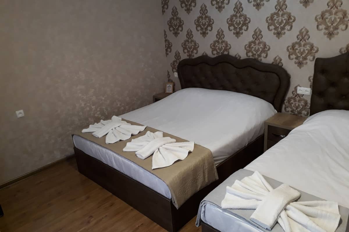 Ein Hotelzimmer mit zwei Betten, jeweils mit ordentlich gefalteten Handtüchern und einem braunen Kopfteil.