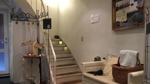 A staircase with a white railing, a small table with a candle and flowers, a basket with a towel, and a framed picture on the wall. - Sovdejligt (Hillerod)