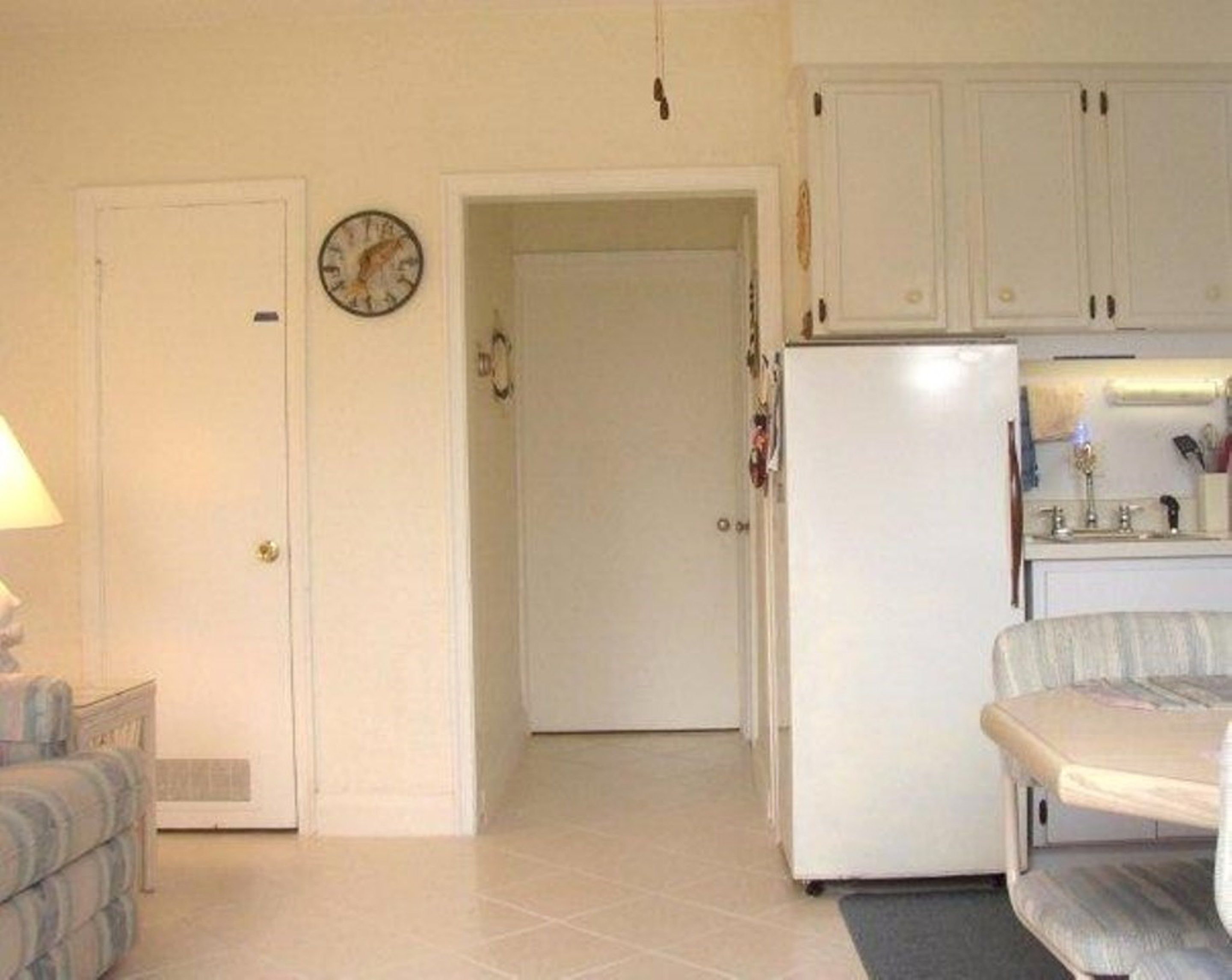 A compact kitchen with white cabinets, a refrigerator, and a dining area with a table and chairs.