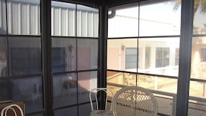 A conservatory with a table and two chairs, a small bench, and a view of the outside. - Venice Villas on the Beach (Venice)