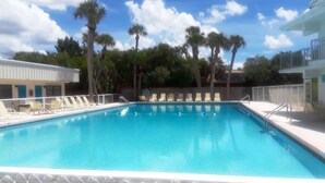 A swimming pool with lounge chairs and palm trees in the background. - Venice Villas on the Beach (Venice)