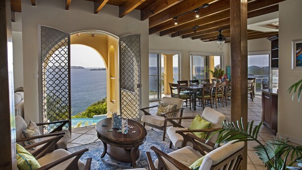 A spacious living area with a view of the sea, furnished with chairs and a coffee table.