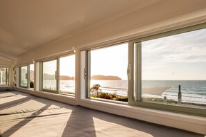 Una habitación con ventanas amplias, vista al mar y un balcón con barandilla.