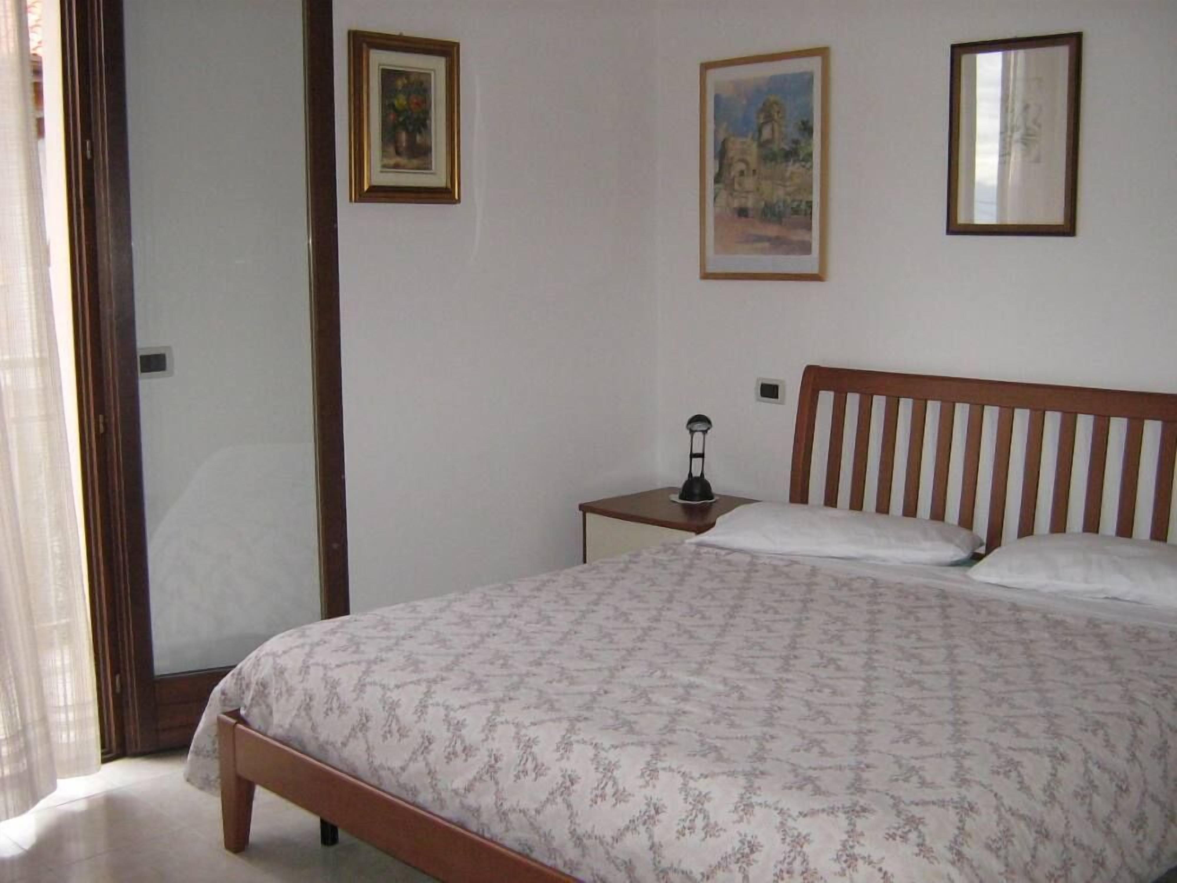 A bedroom with a bed, a nightstand, and two framed pictures on the wall.