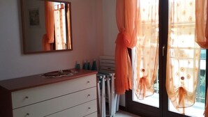 Un dormitorio con un aparador, un espejo y una ventana con cortinas traslúcidas.