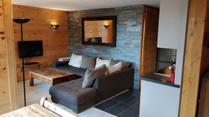 A cozy living area with a grey sofa, wooden coffee table, and a flat-screen TV mounted on the wall. - Valmorel Duplex, 3 bedrooms, 6-8 pers - Skis at your feet, in the heart of the resort (Les Avanchers-Valmorel)