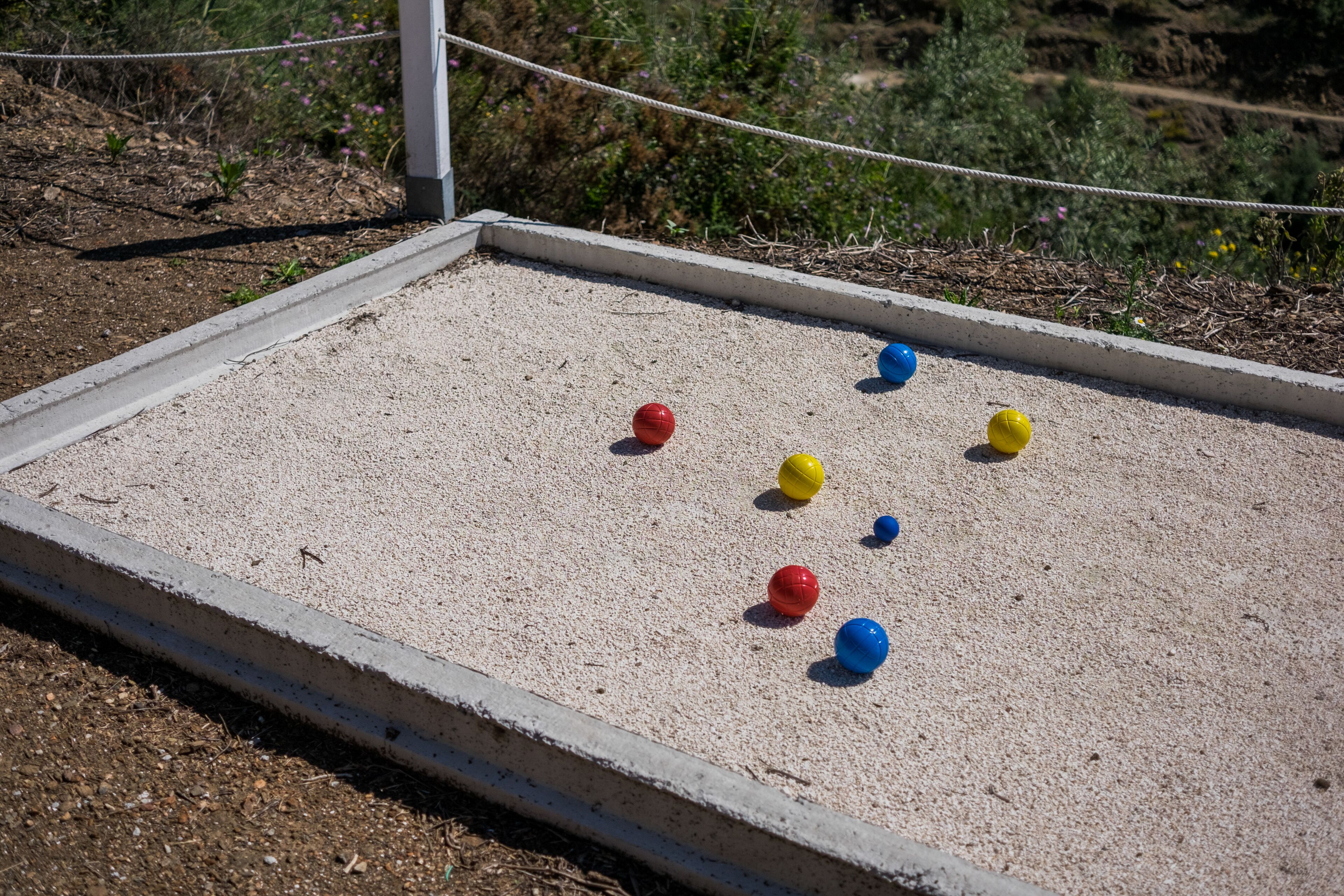 A sandbox with colorful balls and a rope boundary.