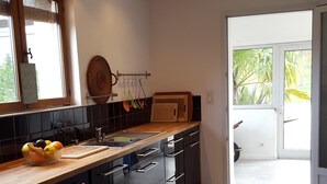 Una cocina moderna con armarios negros, encimera de madera y vistas al exterior a través de un ventanal corredero.