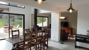 Un comedor con una mesa y sillas de madera, una estufa negra y un televisor al fondo.