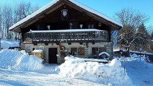 A wooden chalet with a balcony, surrounded by snow.
