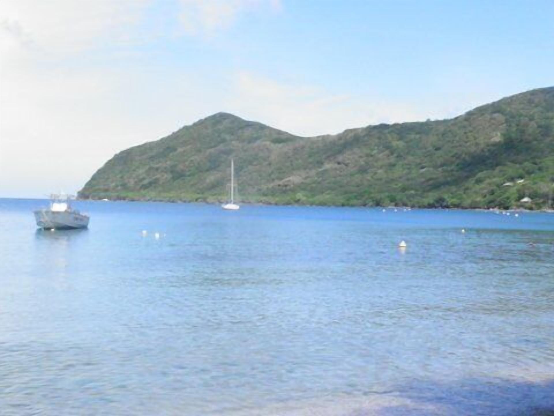 A boat on calm waters with a hilly landscape in the background.