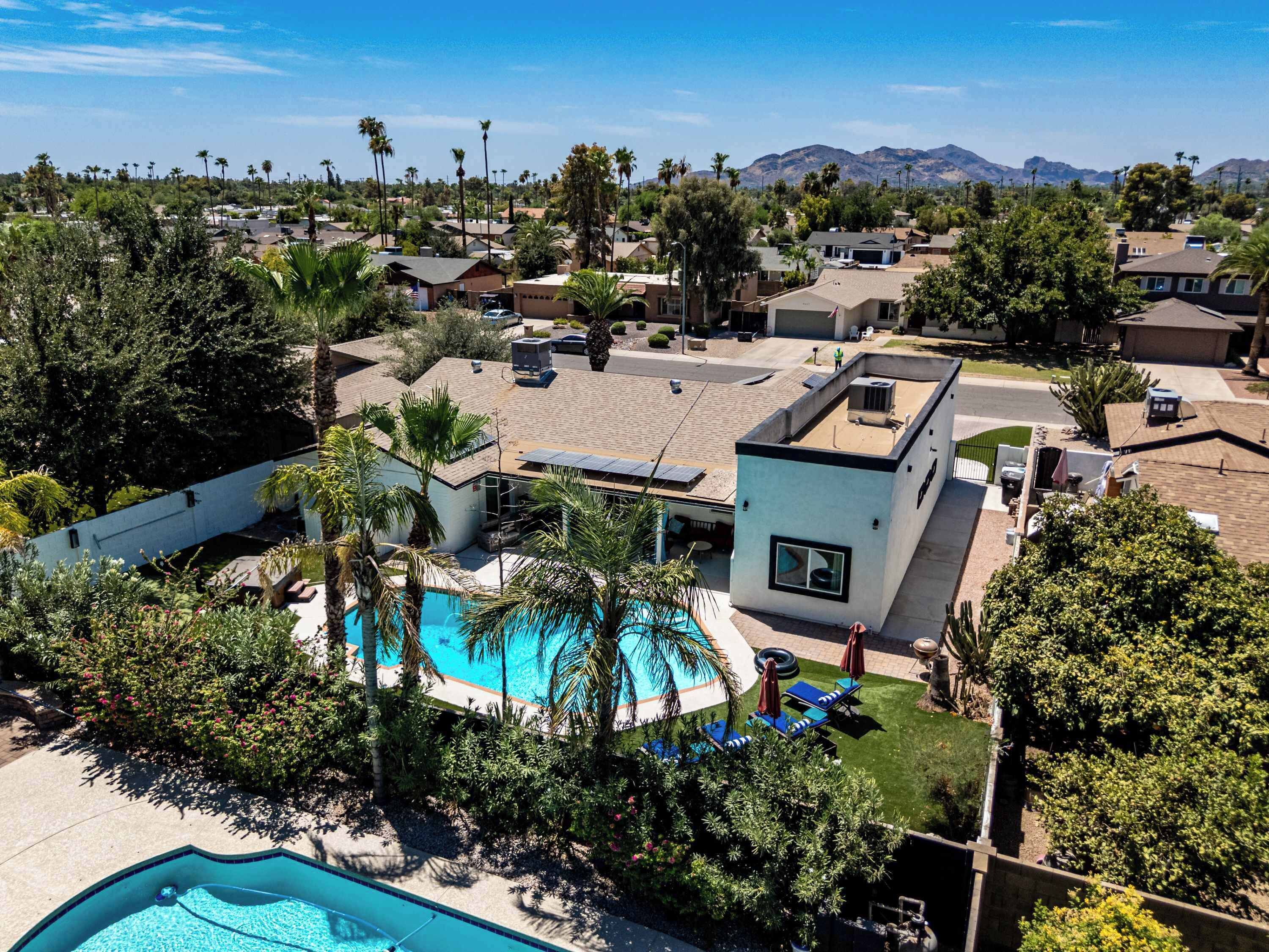 A residential area with a swimming pool, a modern house, and a mountain backdrop.