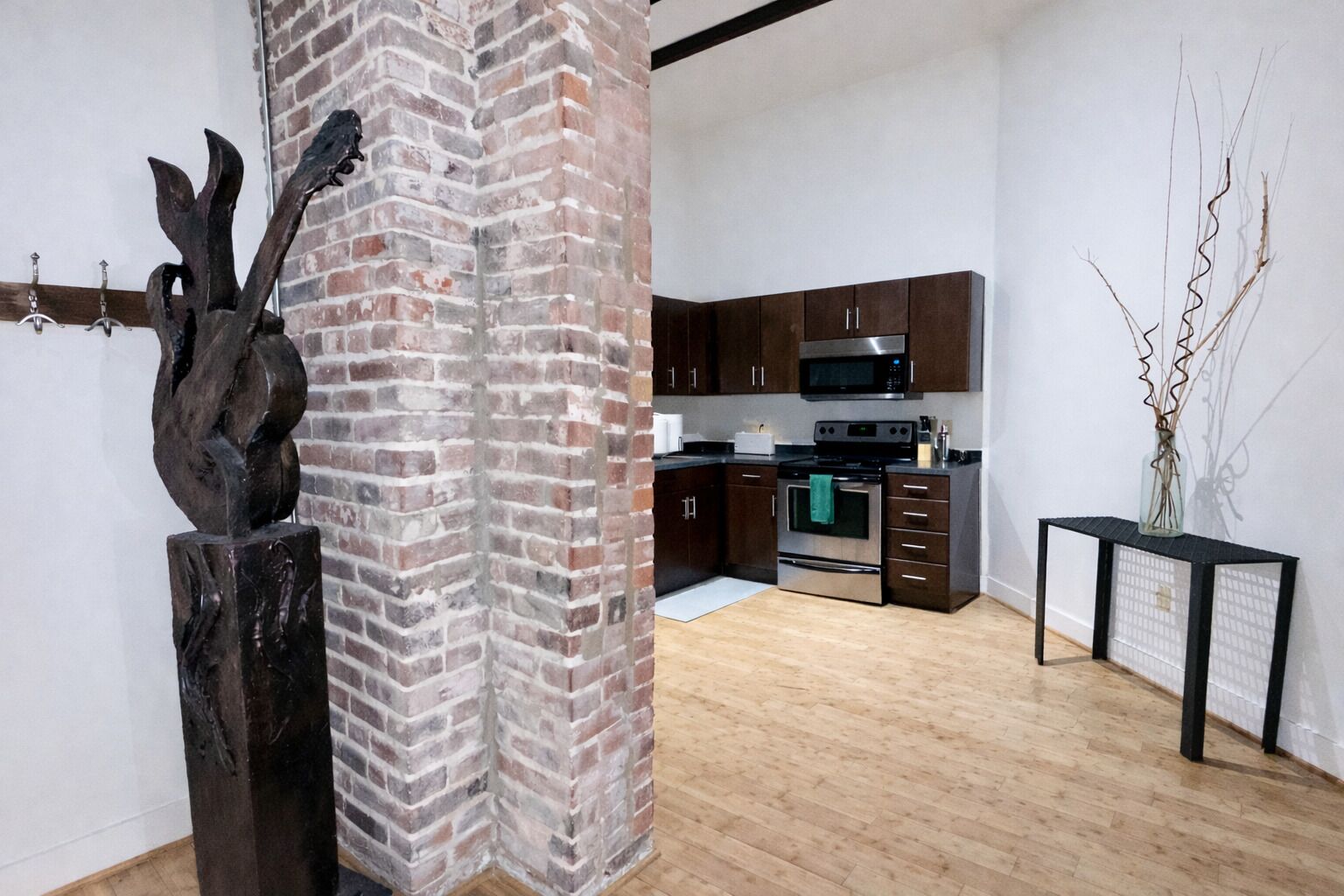 Una cocina moderna con gabinetes de madera oscura, electrodomésticos de acero inoxidable y una pared decorativa de ladrillo.