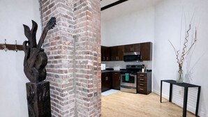 A modern kitchen with dark wooden cabinets, stainless steel appliances, and a brick accent wall. - Downtown Music City Loft living! ~Steps to the Ryman and Broadway (Nashville)
