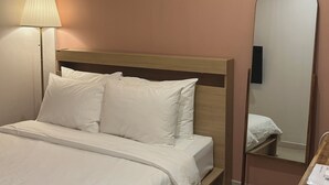 Une chambre d’hôtel avec un lit, une lampe de chevet et un miroir.