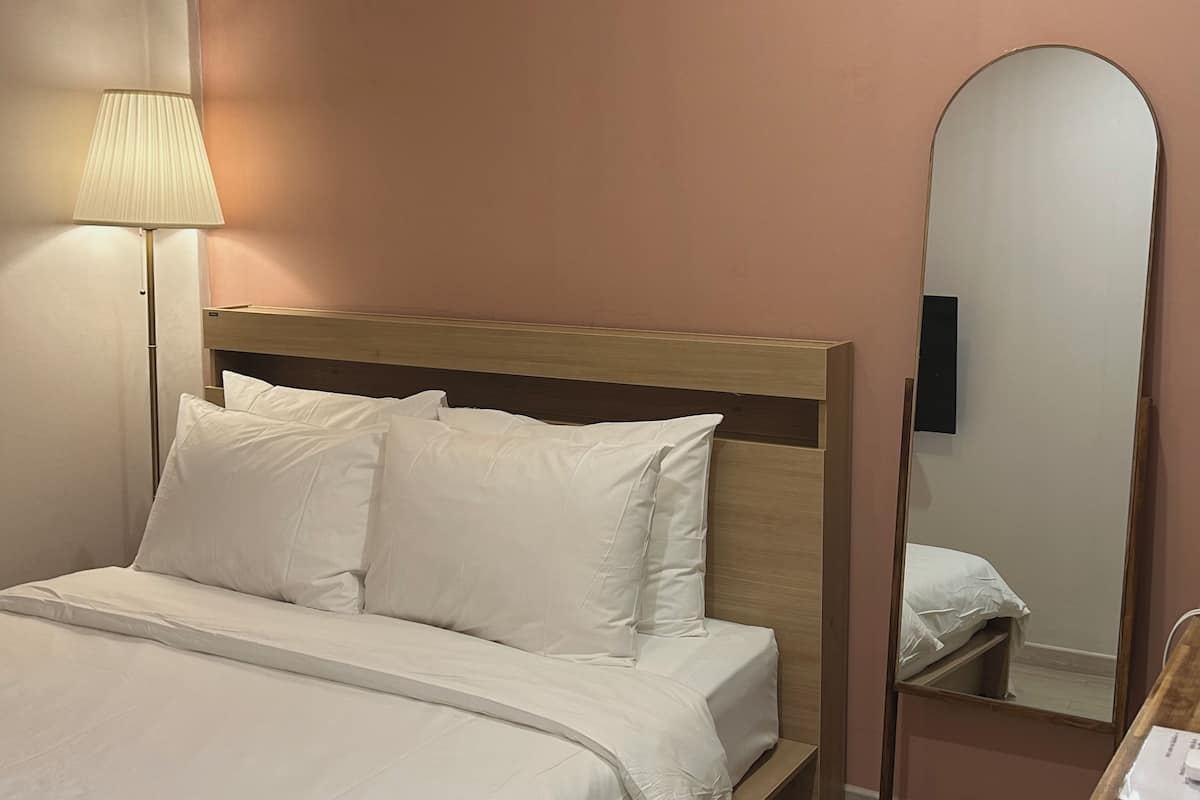 A hotel room with a bed, a bedside lamp, and a mirror.
