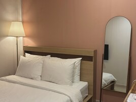 A hotel room with a bed, a bedside lamp, and a mirror.