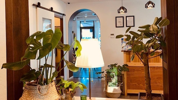 Un couloir bien éclairé, doté d’un sol en marbre, de plantes en pot, d’une lampe et de certificats encadrés accrochés au mur.