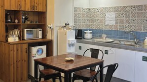 Une cuisine avec des meubles en bois, une table à manger avec des chaises, un four à micro-ondes, une machine à café et un évier.
